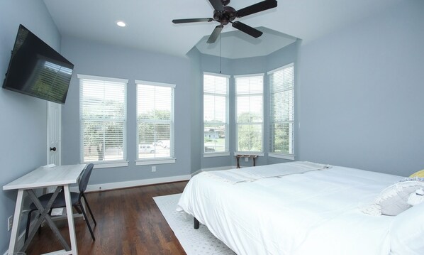 A bedroom with a bed, a desk, and a TV mounted on the wall.