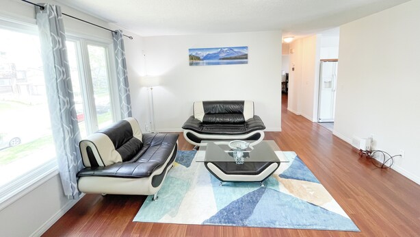 A living room with a sofa, a chair, a coffee table, and a painting on the wall. - 2 Bed rooms, 3 beds with garage for a cozy stay in Calgary (Calgary)
