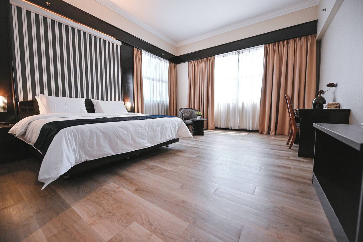 A modern hotel room with a large bed, a desk, and a chair.