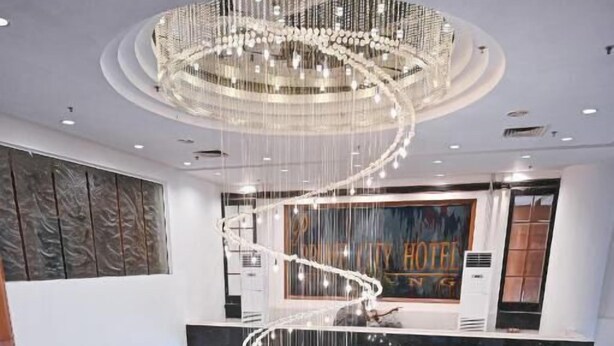 A hotel lobby with a central spiral staircase, a chandelier, and a reception desk.