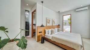 Une chambre à coucher moderne avec un grand lit, une table de chevet, une plante en pot et une vue sur l’extérieur.