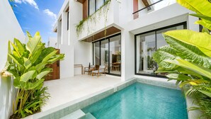 Une maison moderne dotée d’une piscine, de grandes fenêtres et d’une végétation luxuriante.