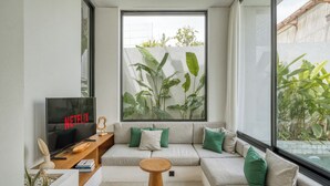Un salon moderne doté d’une grande fenêtre, d’un canapé, d’une table basse et d’un téléviseur affichant le logo « NETFLIX ».