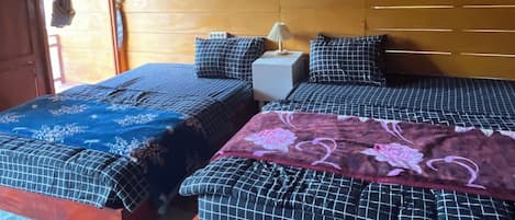 Un dormitorio de cabaña de madera con dos camas, una mesita de noche y una lámpara colgante.