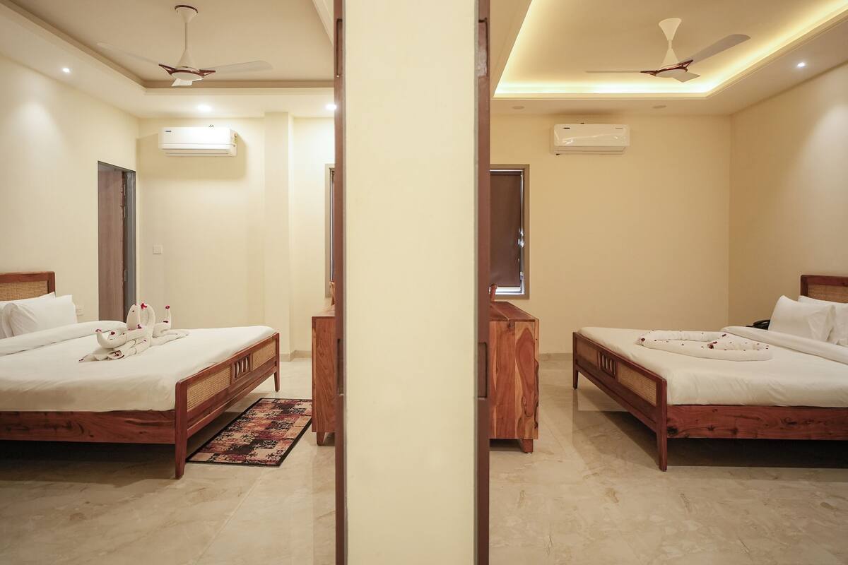 A mirrored view of a hotel room with two beds, wooden headboards, white linens, a small wooden nightstand, and ceiling fans.