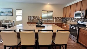 A modern kitchen with a central island, wooden cabinets, and stainless steel appliances. - Quiet Modern Home Spacious & Work-Friendly (Beaumont)