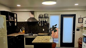 A modern kitchen with a central island, black cabinetry, and a marble floor. - Family- and Pet-Friendly Downtown Home, Close to Everything (Stevensville)