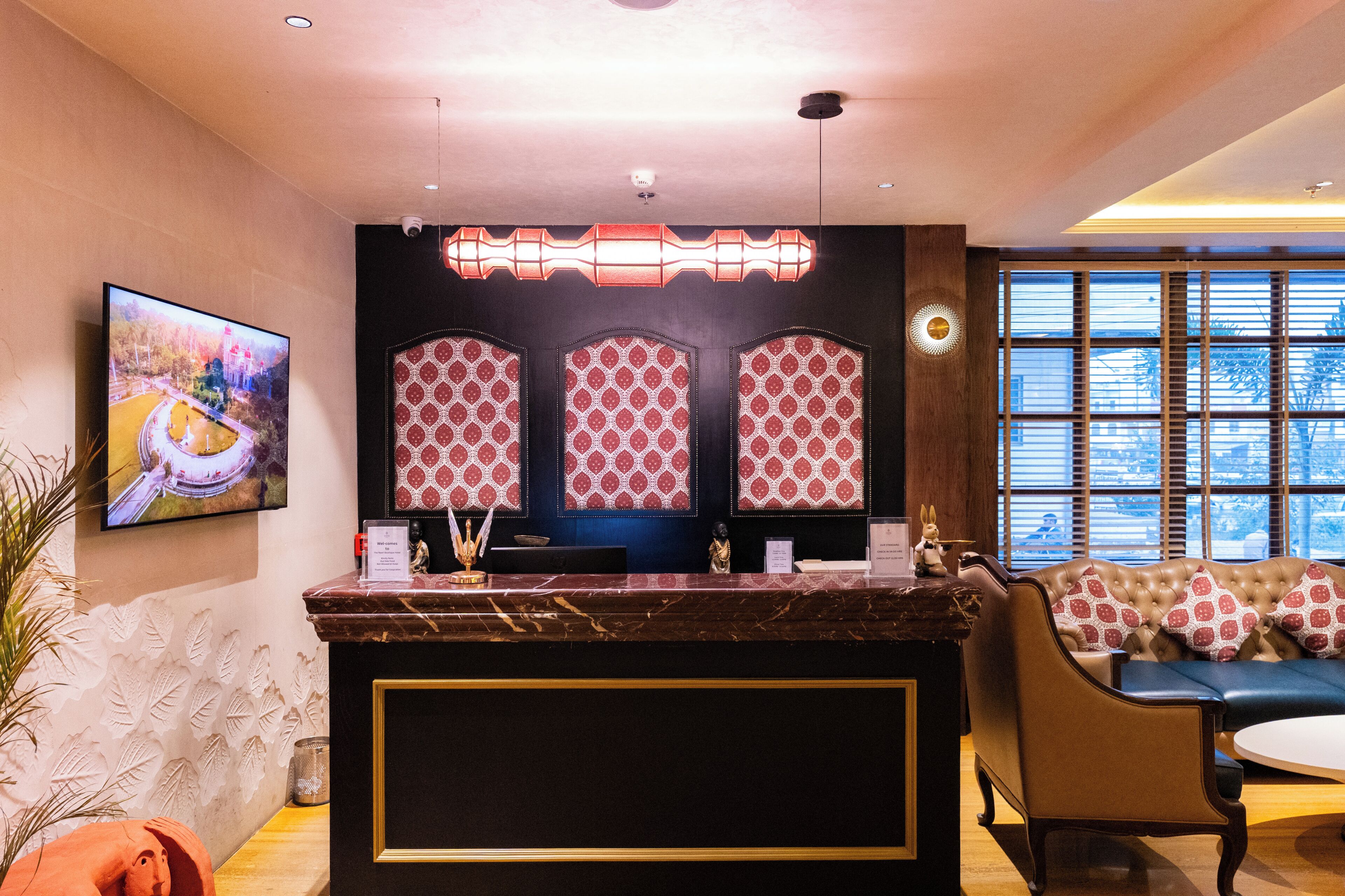 Un'area reception con un bancone in marmo, pannelli murali decorati, un televisore e un divano con cuscini fantasia.