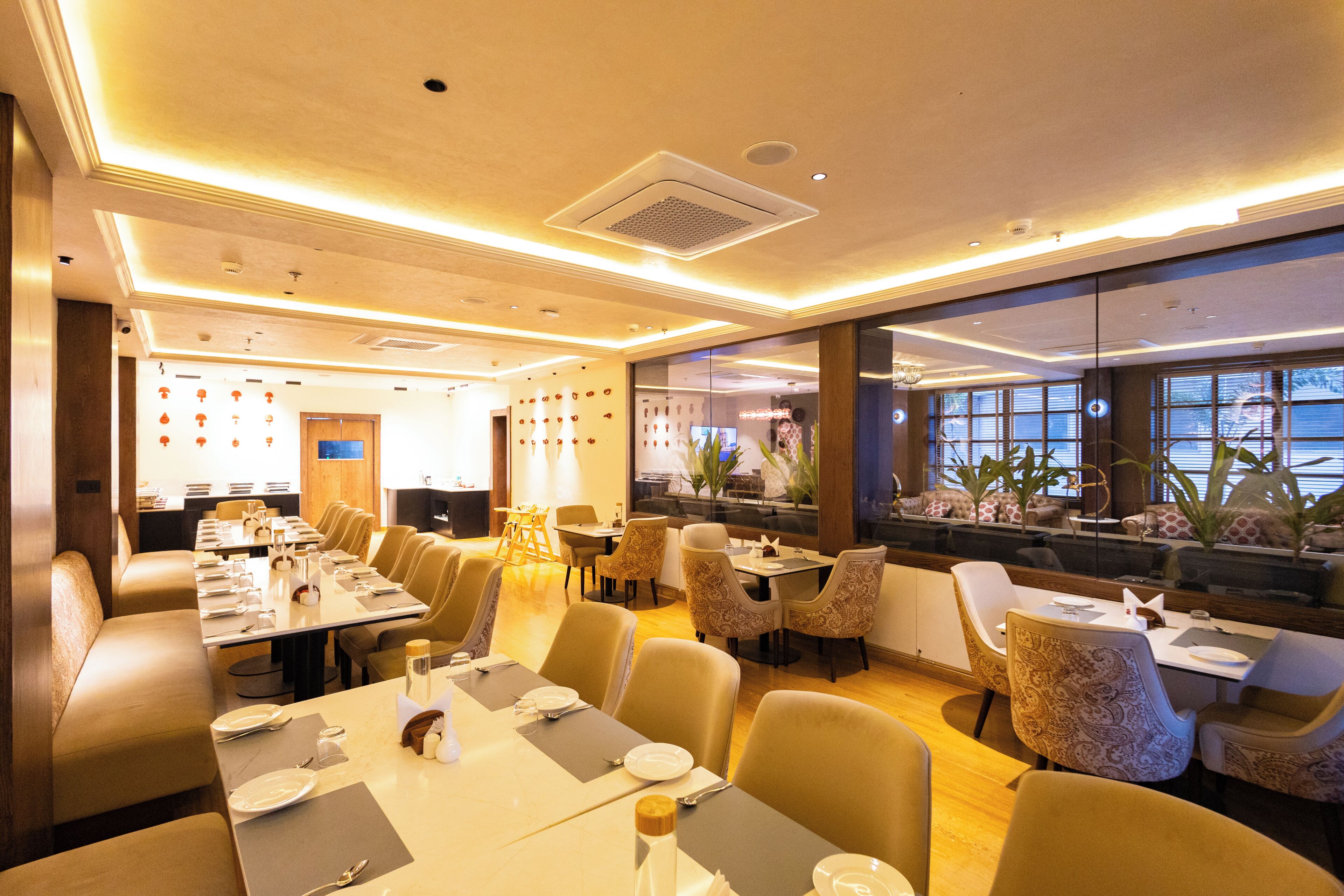 A restaurant with multiple dining tables, chairs, and a view of the sea through large windows.