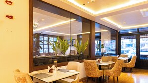 Ein Restaurantinneres mit Tischen, Stühlen, großen Fenstern und Blick auf die Straße.