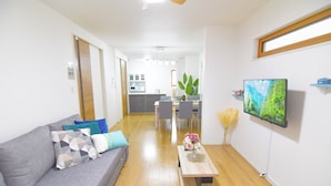 Una sala de estar moderna con un sofá gris, una mesa de centro de madera y un televisor en la pared.