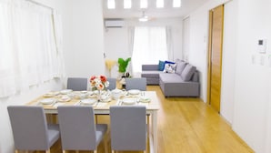 Una sala de estar moderna con comedor, que incluye un sofá, una mesa preparada para una comida y un ventilador de techo.