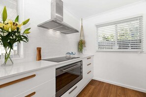 Eine moderne Küche mit weißen Schränken, einer Edelstahl-Dunstabzugshaube und einem eingebauten Backofen.