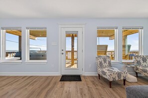 Ein Zimmer mit Holzboden, einer weißen Tür und zwei gemusterten Sesseln.