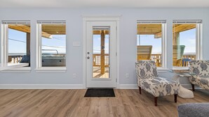 Une pièce avec un plancher en bois, une porte blanche et deux fauteuils à motifs.