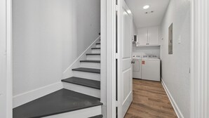 Un couloir étroit avec un escalier menant à une buanderie.