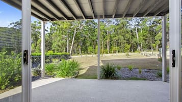 A modern outdoor space with a concrete floor, surrounded by greenery and trees.