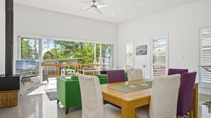A modern living room with a dining area, large windows, and a view of the outdoors. - Allawah in North Bendalong (Bendalong)