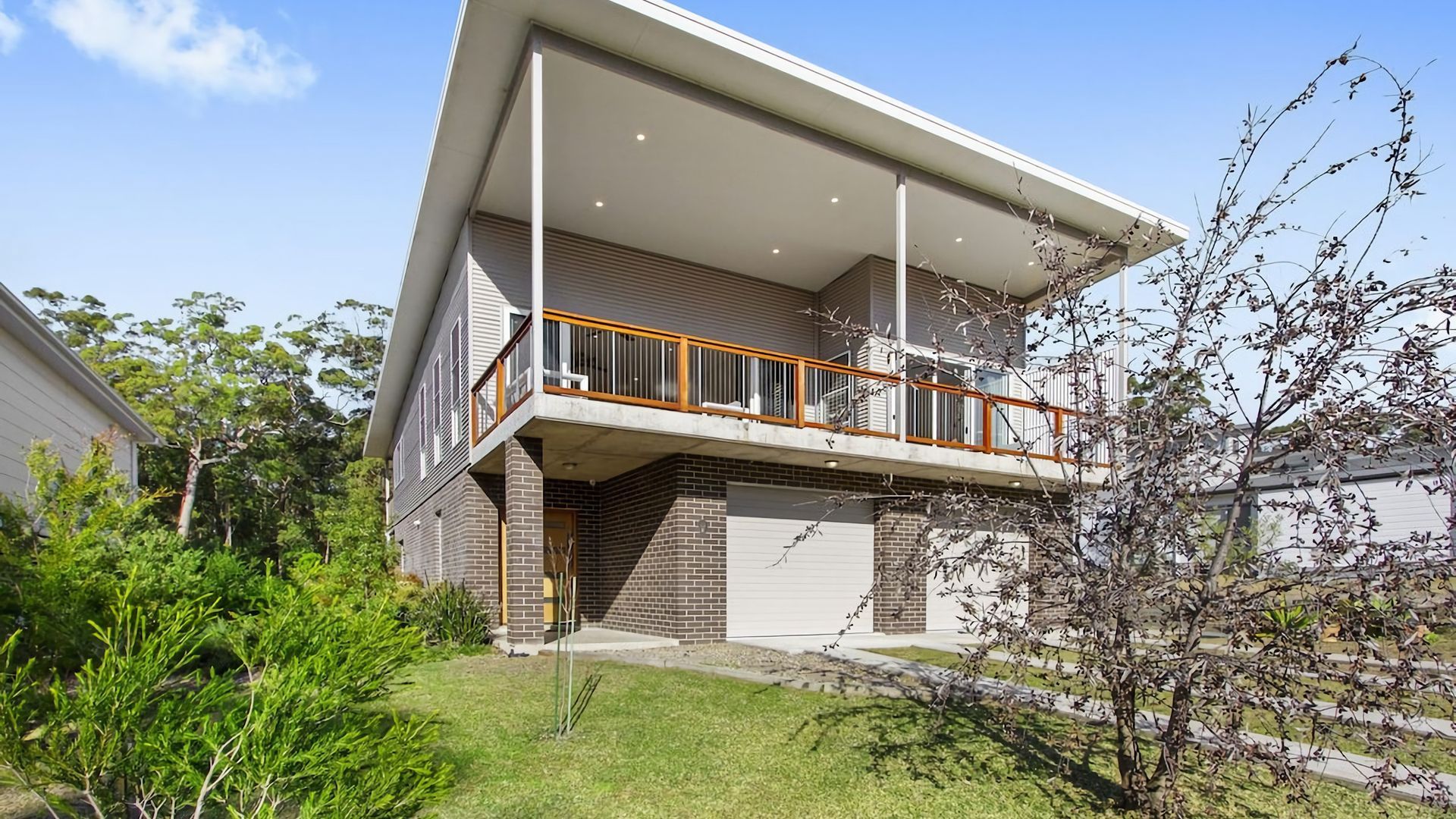 A two-story house with a balcony, garage, and a well-maintained lawn.