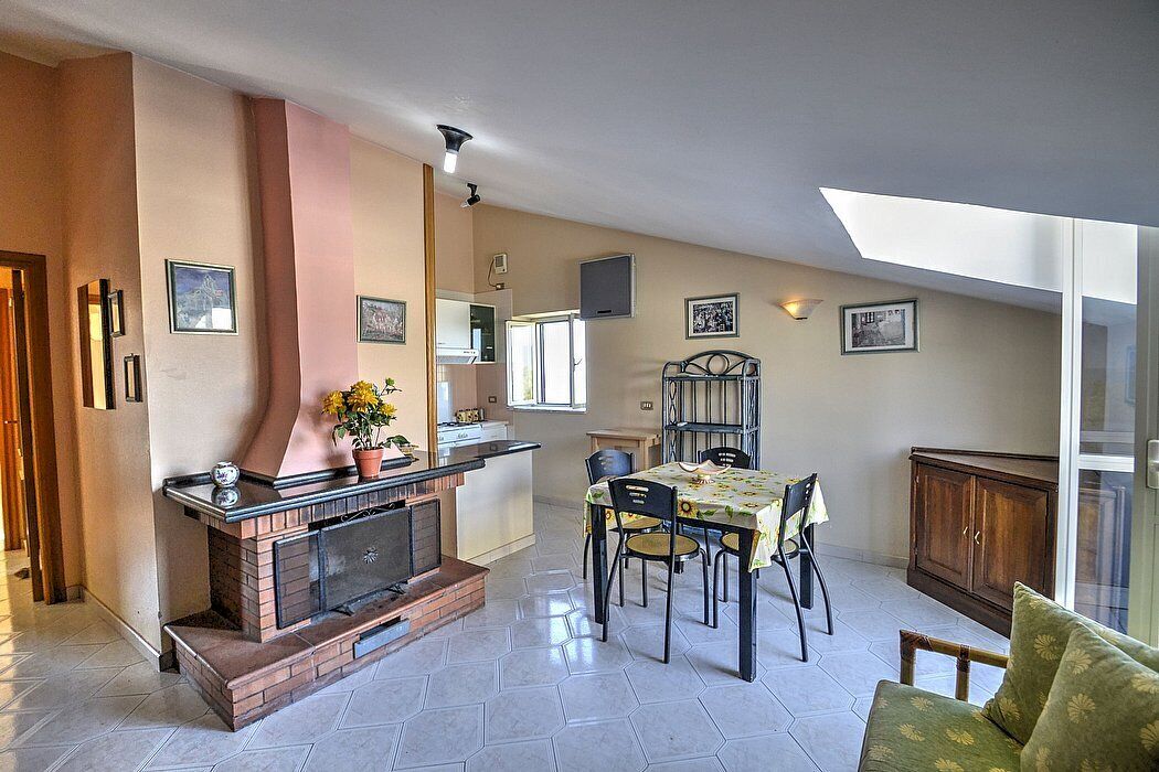 A dining area with a brick fireplace, a dining table with chairs, and a sofa.