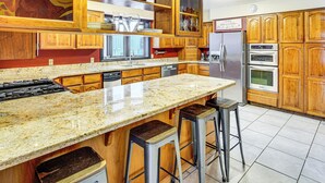 Eine Küche mit Holzausstattung, einer Granit Arbeitsplatte, einem Edelstahlkühlschrank und einem Kombidämpfer.