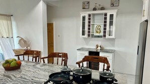 Une cuisine équipée d’une cuisinière à gaz, de chaises en bois, d’un plan de travail en marbre et d’un meuble dont la porte est ornée de la lettre « B ».
