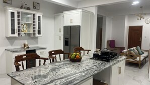 Une cuisine moderne avec des meubles blancs, un plan de travail en marbre et un réfrigérateur encastré.