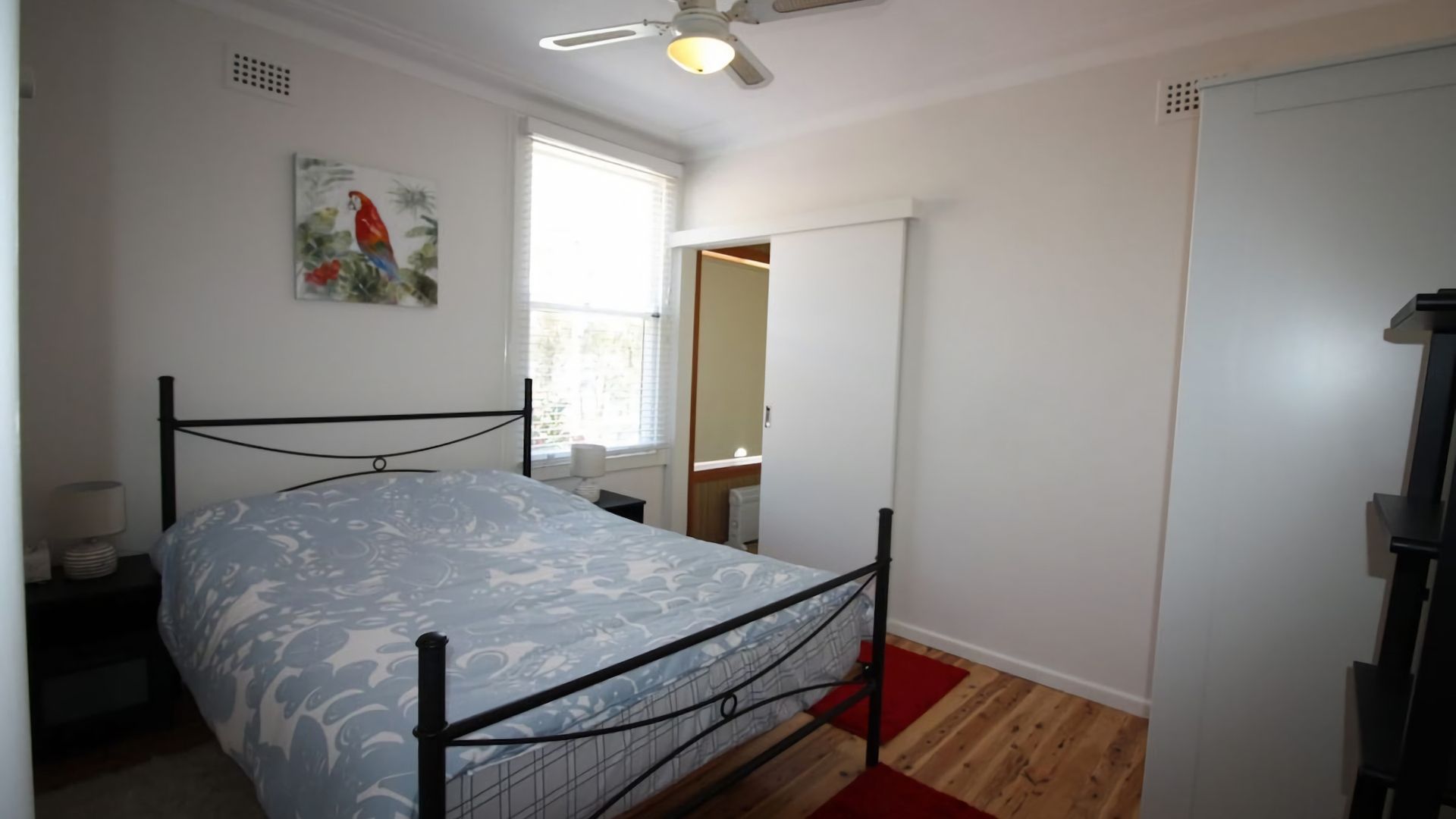Une chambre à coucher avec un lit, un ventilateur de plafond, une fenêtre et une porte.
