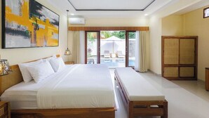 Habitación de hotel con una cama grande, una mesita de noche, un armario y vistas a un espacio exterior con piscina y sombrillas.