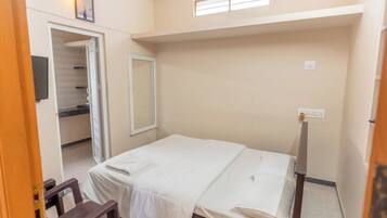 Una habitación pequeña con cama individual, un armario, un espejo y una ventana.