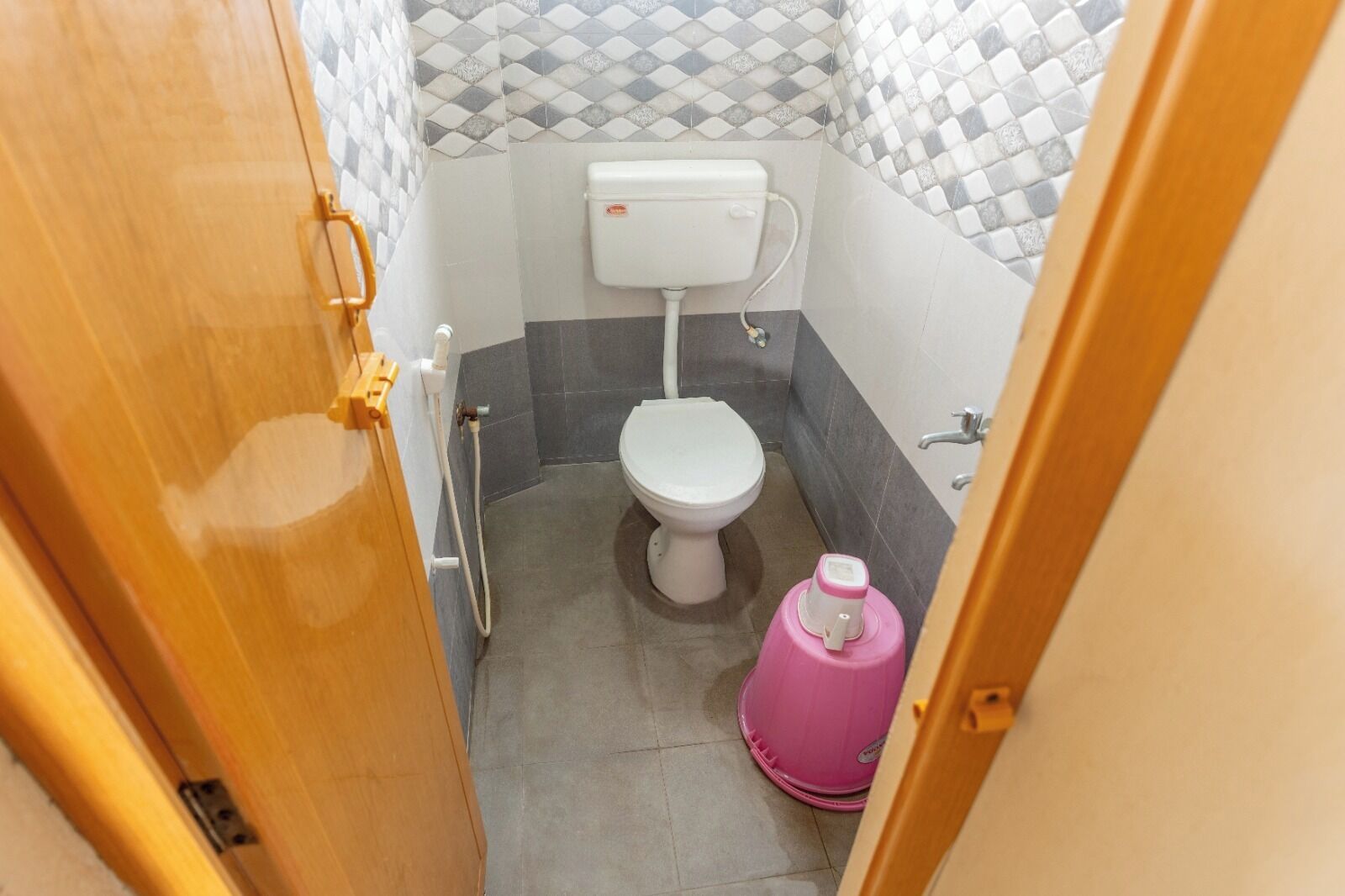 A small bathroom with a toilet, a shower, and a pink water heater.