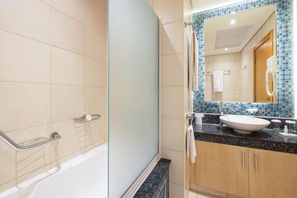A bathroom with a bathtub, a sink, and a mirror.