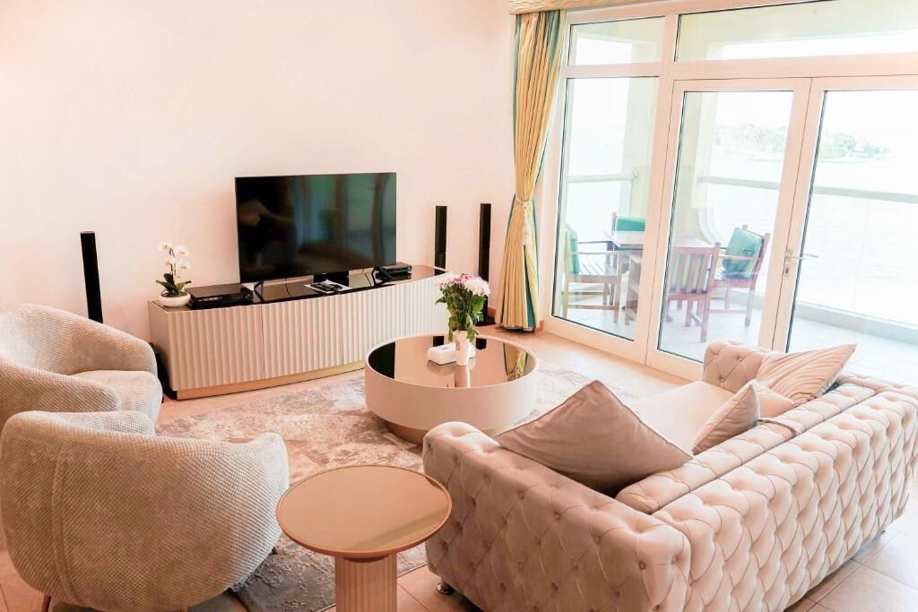 Ein modernes Wohnzimmer mit Flachbildfernseher, rundem Couchtisch, Sofa und Sessel.
