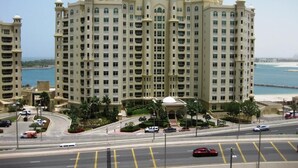 A multi-story hotel with a central courtyard, a beach view, and a parking area. - Highend Shoreline Prestige Palm Jumeirah (Dubai)