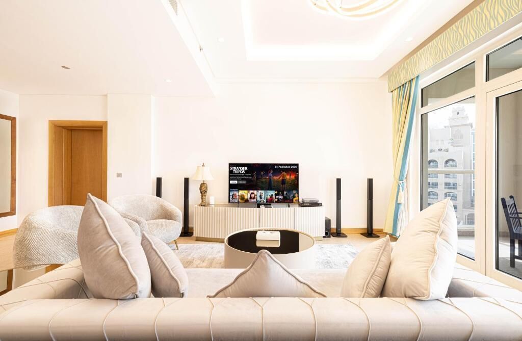 Uma sala de estar moderna com um sofá, uma mesa de centro e uma televisão de tela plana em um suporte.