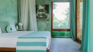 Um quarto com cama, janela com cortinas, quadro na parede e pequena mesa de cabeceira com abajur.