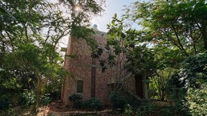 A rustic stone building surrounded by dense foliage, with a clear path leading to the entrance.