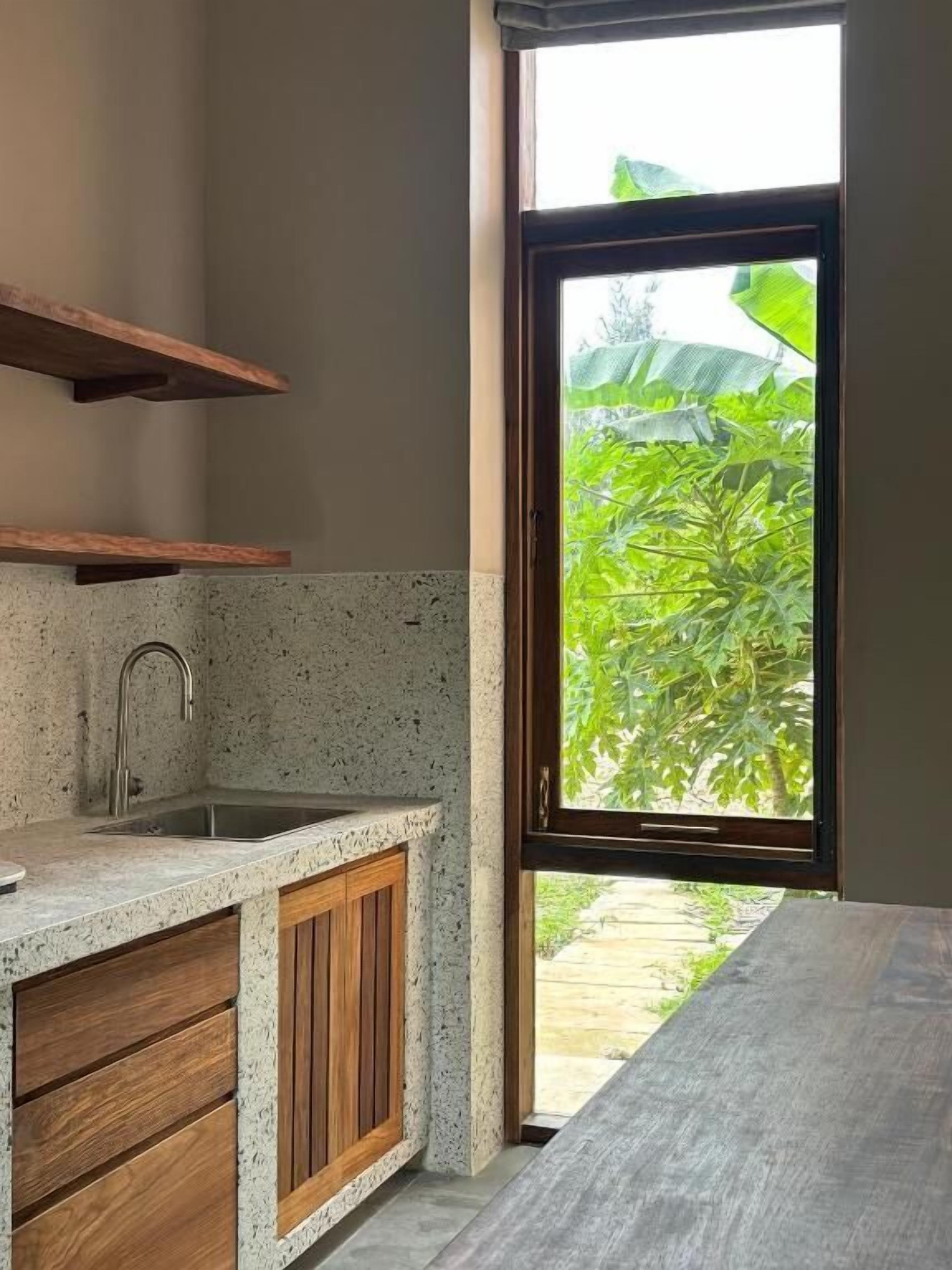 Una cocina con encimera de granito, armarios de madera y ventana con vista a la vegetación.