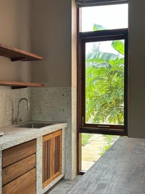 Una cocina con encimera de granito, armarios de madera y ventana con vista a la vegetación.