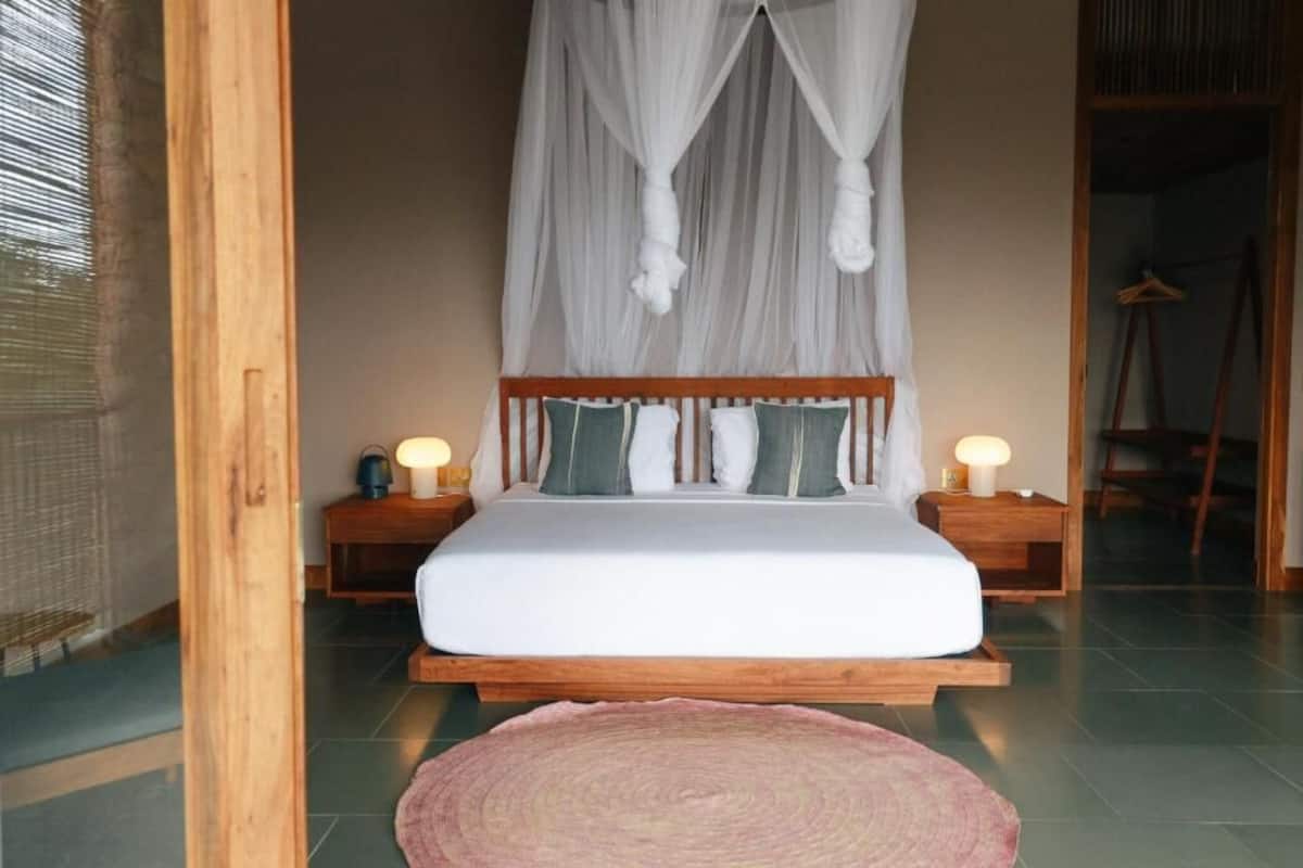 A bedroom with a bed, bedside lamps, a canopy, and a bedside table.