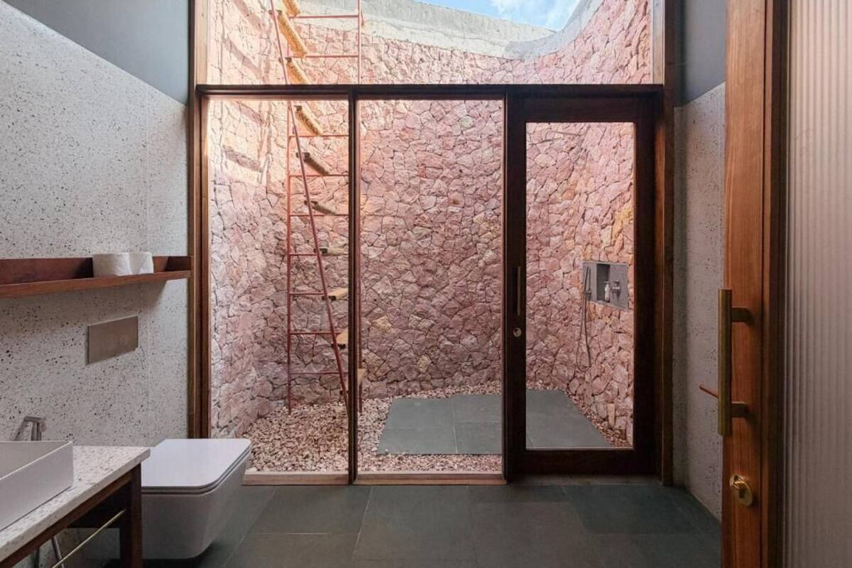 A bathroom with a stone wall, a shower area, and a skylight.