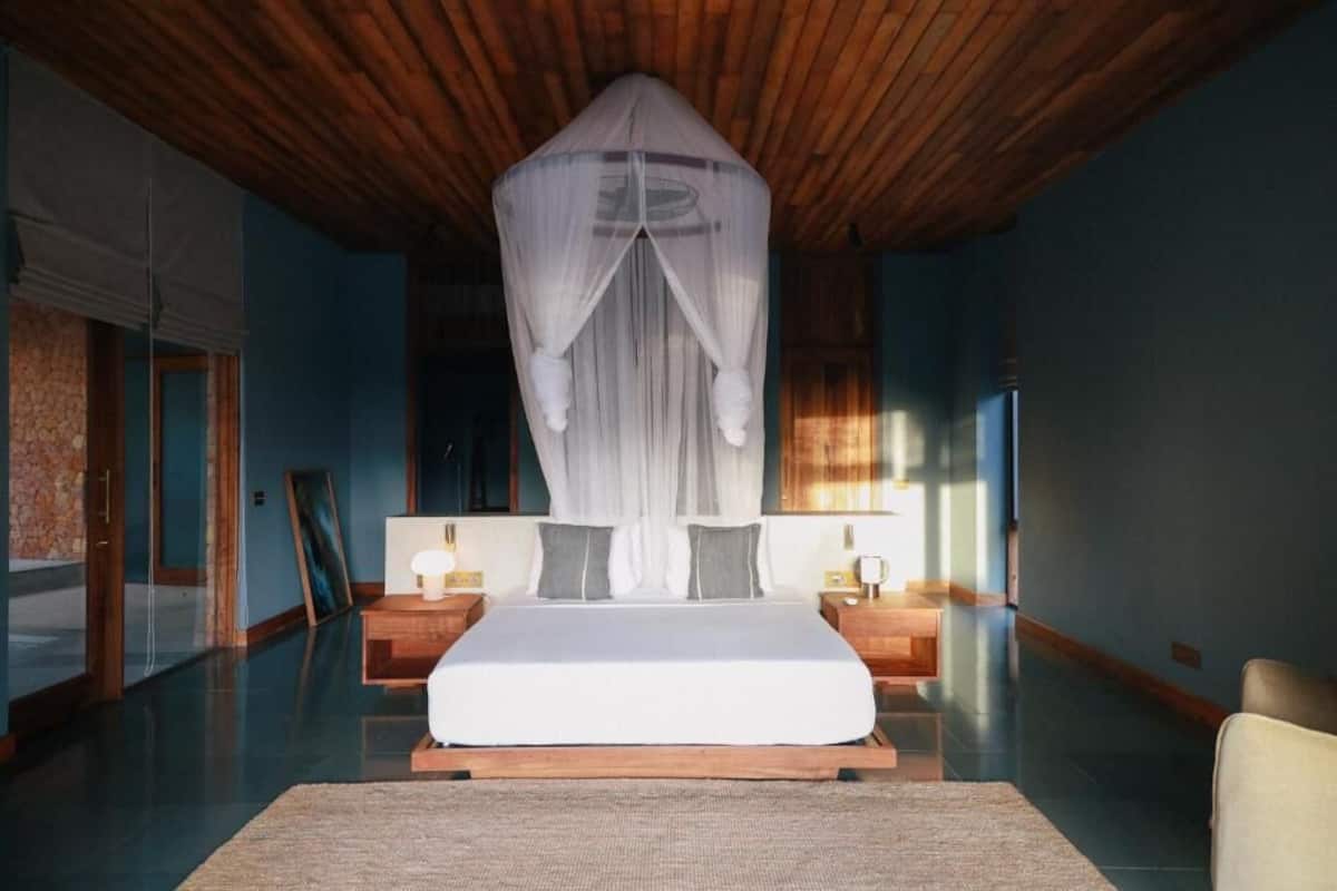 A bedroom with a bed, bedside tables, a canopy, and a view of the outside.