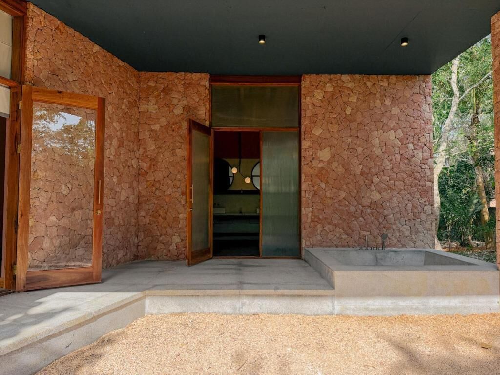 Une façade en pierre avec une porte en bois et une entrée en retrait.