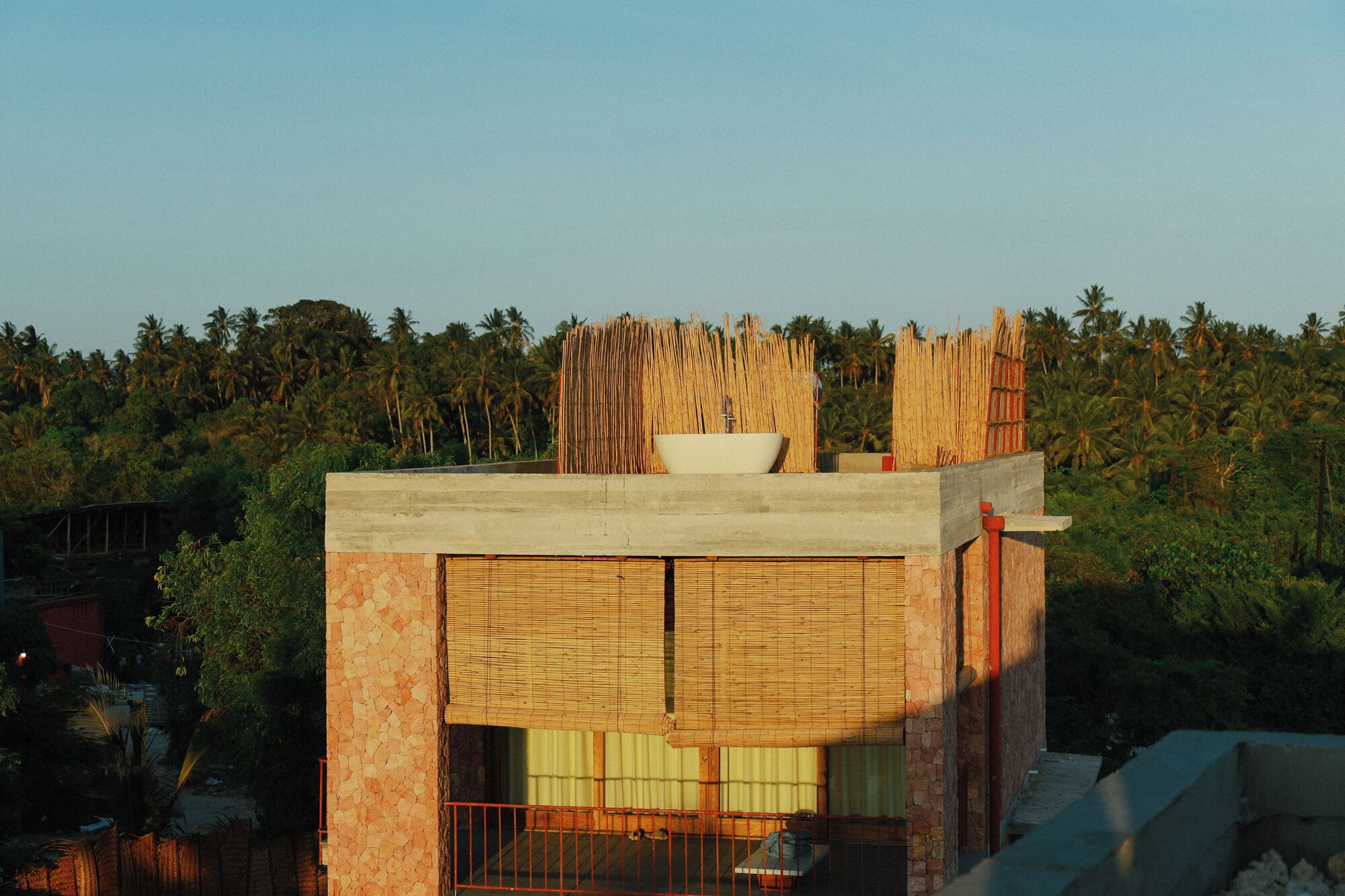 Un edificio con un ventanal grande, estructura de hormigón y valla de madera.