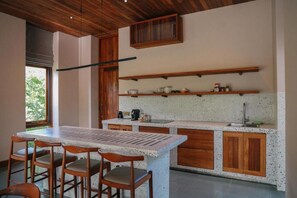 A kitchen with a central island, wooden chairs, and built-in shelves.