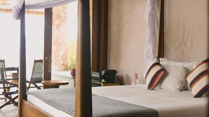 A bedroom with a canopy bed, a small table, and a chair.