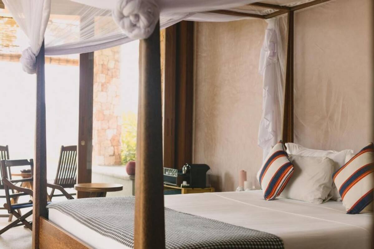 A bedroom with a canopy bed, a small table, and a chair.