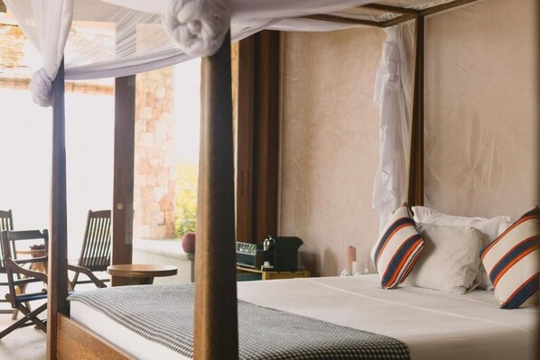 Un dormitorio con cama con dosel, una mesita y una silla.