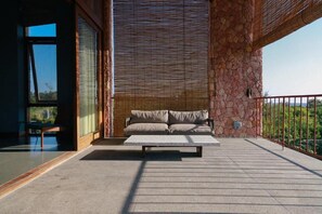Un área de estar moderna al aire libre con un muro de piedra, un banco acolchado y vistas a zonas verdes.