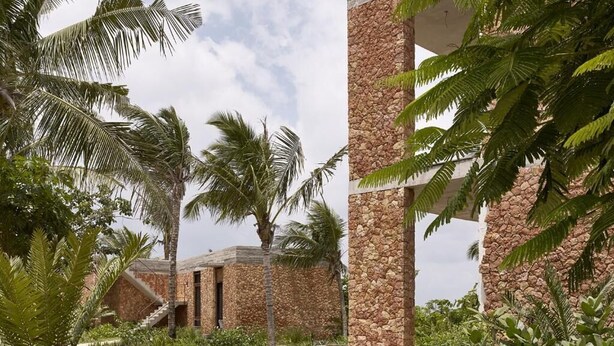 A resort with stone pillars, palm trees, and a building with a stone facade.